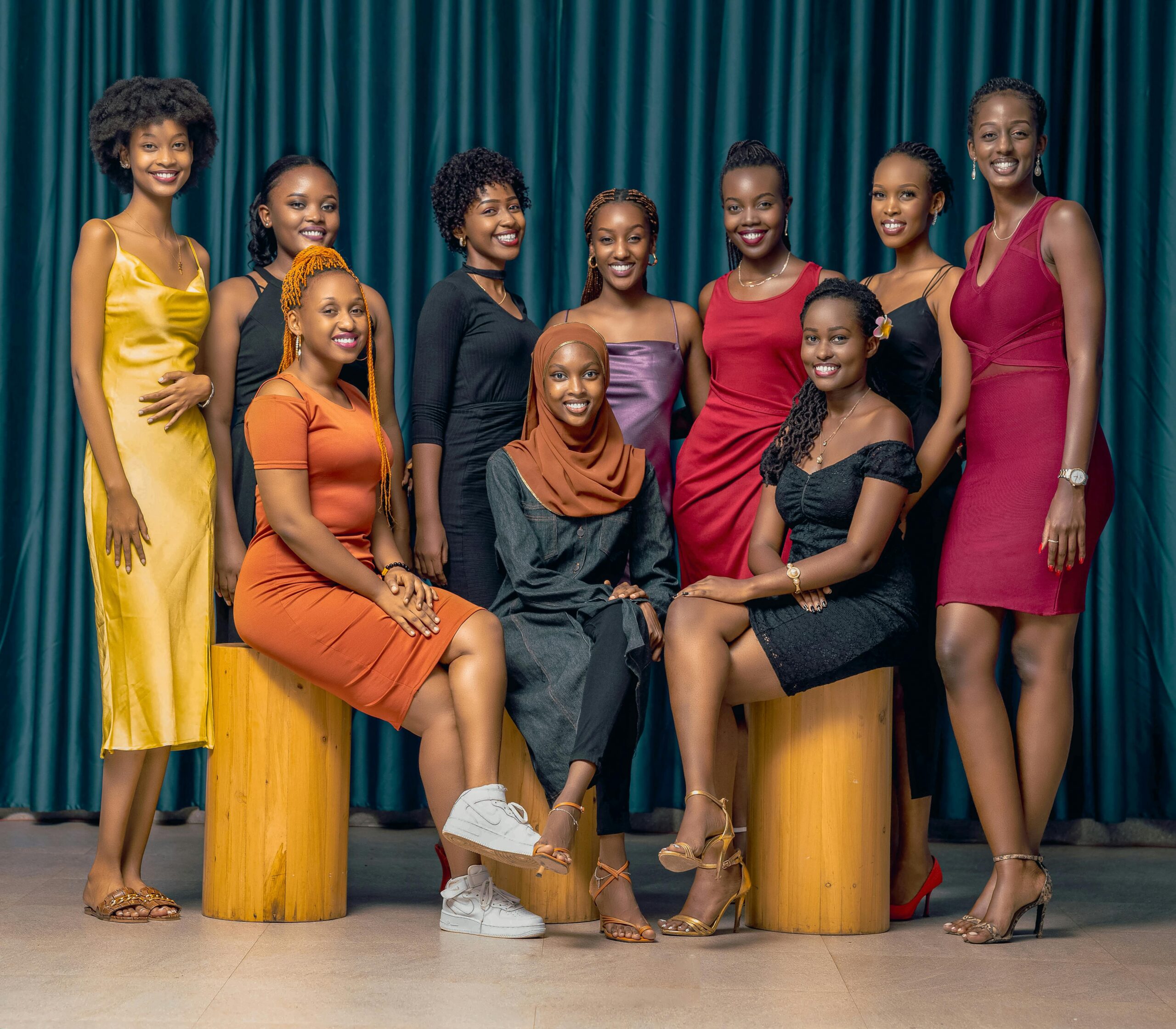 A stylish group of diverse women posing in elegant dresses indoors.
